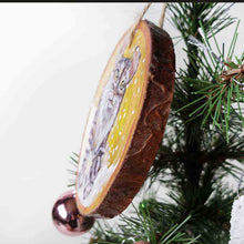 Load image into Gallery viewer, A wooden ornament with art of an American Curl cat with golden eyes, watching the snow fall
