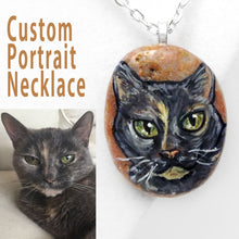 Load image into Gallery viewer, A small beach stone is handpainted with a portrait of a grey cat and crafted into a necklace.
