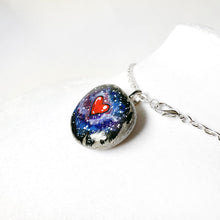 Load image into Gallery viewer, a beach stone has been hand painted with a heart surrounded by outer space and stars, and hand crafted as either a keepsake stone, magnet, or pendant necklace
