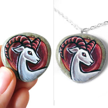Load image into Gallery viewer, a beach rock painted with the zodiac art of aries: a white ram with dark red horns. this stone is available as a keepsake, magnet or pendant necklace
