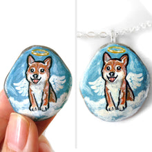 Load image into Gallery viewer, a smooth beach stone, hand painted with a portrait of a shiba inu dog as an angel, sitting on clouds against a light blue sky. available as a keepsake or pendant necklace
