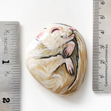 Load image into Gallery viewer, A small beach rock painted with a portrait of an albino ferret, next to two rulers, measures 1 7/8" x 1 9/16".
