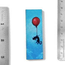 Load image into Gallery viewer, a wood rectangle hand painted with art of a black cat, with a red balloon, floating through a blue sky. available as a keepsake or pendant necklace
