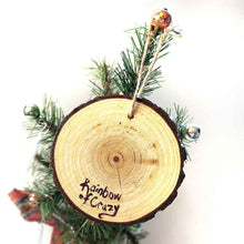 Load image into Gallery viewer, a round wood ornament, hand painted with a portrrait of a black cat's face, with yellow eyes, against a soft green background, the back signed with, Rainbow of Crazy
