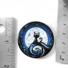 Load image into Gallery viewer, a wood disc, hand painted with a small black cat sitting on a curly hill, against a large full moon and starry night sky. this piece is available as a keepsake o rpendant necklace
