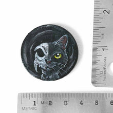 Load image into Gallery viewer, a circle shaped wood disc, hand painted with a split image: a black cat's face on the right side, and a cat skull on the left side. available as a keepsake or pendant necklace
