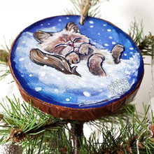 Load image into Gallery viewer, A Christmas tree wood ornament, hand painted with art of a Himalayan cat sleeping on snow.
