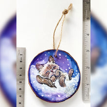 Load image into Gallery viewer, A Christmas tree wood ornament, hand painted with art of a Himalayan cat sleeping on snow.
