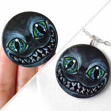 Load image into Gallery viewer, a portrait of an evil looking Cheshire Cat with an evil smile, hand painted on a wood disc. it's available as a keepsake or pendant necklace
