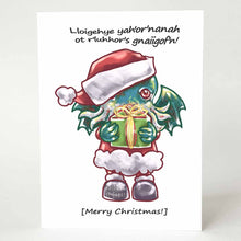 Load image into Gallery viewer, a greeting card with an illustration of a Cthulhu dressed as Santa Claus, holding a gift. The card reads,  "Lloigehye yah'or'nanah ot r'luhhor's gnaiigof'n!" above and "[Merry Christmas!]" below
