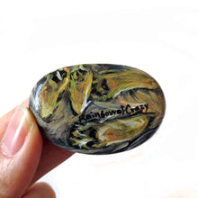 Load image into Gallery viewer, a small beach stone, hand painted with the portrait of a Yorkshire terrier dog, its paws painted on the underside, signed with, rainbow of crazy
