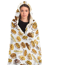 Load image into Gallery viewer, a woman wearing the Happy Cookies Hooded Blanket, featuring 10 illustrated smiling cookies patterned all over, lined with sherpa

