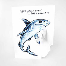 Load image into Gallery viewer, a greeting card with art of a blue shark. text reads, "i got you a card! ... but i eated it". the bottom right corner of the card is ripped off and hangs from the shark's mouth.
