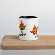 Load image into Gallery viewer, Ah 11 oz white ceramic mug with black handle and interior, printed on the front and back with an image of two smiling maple leaves, and the words, "I be-leaf in you"
