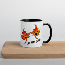 Load image into Gallery viewer, Ah 11 oz white ceramic mug with black handle and interior, printed on the front and back with a graphic of two smiling maple leaves, and the words, "I be-leaf in you"
