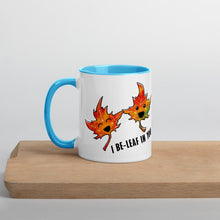Load image into Gallery viewer, Ah 11 oz white ceramic mug with blue handle and interior, printed on the front and back with art of two smiling maple leaves, and the words, "I be-leaf in you"

