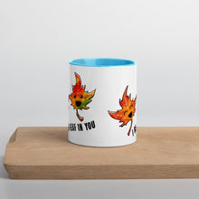 Load image into Gallery viewer, Ah 11 oz white ceramic mug with blue handle and interior, printed on the front and back with art of two smiling maple leaves, and the words, "I be-leaf in you"
