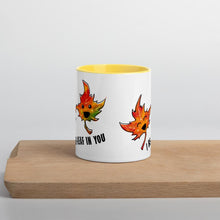 Load image into Gallery viewer, Ah 11 oz white ceramic mug with yellow handle and interior, printed on the front and back with a graphic of two smiling maple leaves, and the words, "I be-leaf in you"
