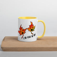 Load image into Gallery viewer, Ah 11 oz white ceramic mug with yellow handle and interior, printed on the front and back with a graphic of two smiling maple leaves, and the words, "I be-leaf in you"
