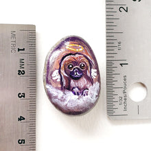 Load image into Gallery viewer, A small beach stone painted with a portrait of a Pekingese dog as an angel, next to two rulers to show its size: 1 7/16" x 1 1/16" or 3.7 cm x 2.7 cm
