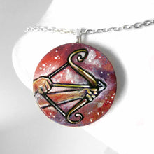 Load image into Gallery viewer, a wood circle pendant, hand painted, depicting the zodiac sign sagittarius: two hands hold a bow, with an arrow, ready to fire
