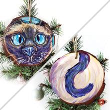Load image into Gallery viewer, A wood ornament featuring art of a siamese cat's face with blue eyes, and it's tail on the back.
