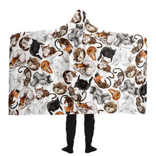 Load image into Gallery viewer, a man wears the Sleepy Cats Hooded Blanket, featuring illustrations of different sleeping cats
