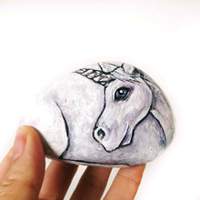 Load image into Gallery viewer, a stone hand painted with the portrait of a unicorn with purple eyes
