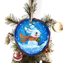 Load image into Gallery viewer, A wood Christmas ornament, hand painted with a white rabbit sitting on the snow with a blue background, with an orange scarf, green mittens, and christmas lights on its ears
