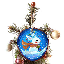 Load image into Gallery viewer, A wood Christmas ornament, hand painted with a white rabbit sitting on the snow with a blue background, with an orange scarf, green mittens, and christmas lights on its ears
